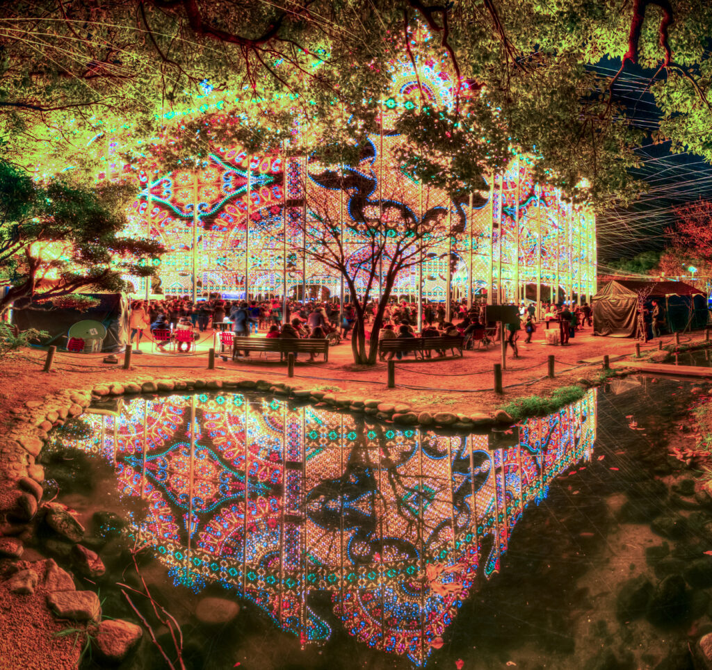 The image featured in this article is a photograph of the Kobe Luminarie, an annual light festival in Kobe, Japan. The vibrant, colorful lights reflected in the water create an otherworldly atmosphere, making the scene appear both real and fantastical. The interplay of light and reflection adds a layer of surrealism, inviting viewers to question what is real and what is an illusion.