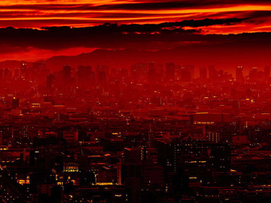 The featured image captures the skyline of Osaka bathed in a stunning red sunset. The fiery hues of the sky contrast sharply with the dark silhouettes of the city, creating a dramatic and captivating scene.