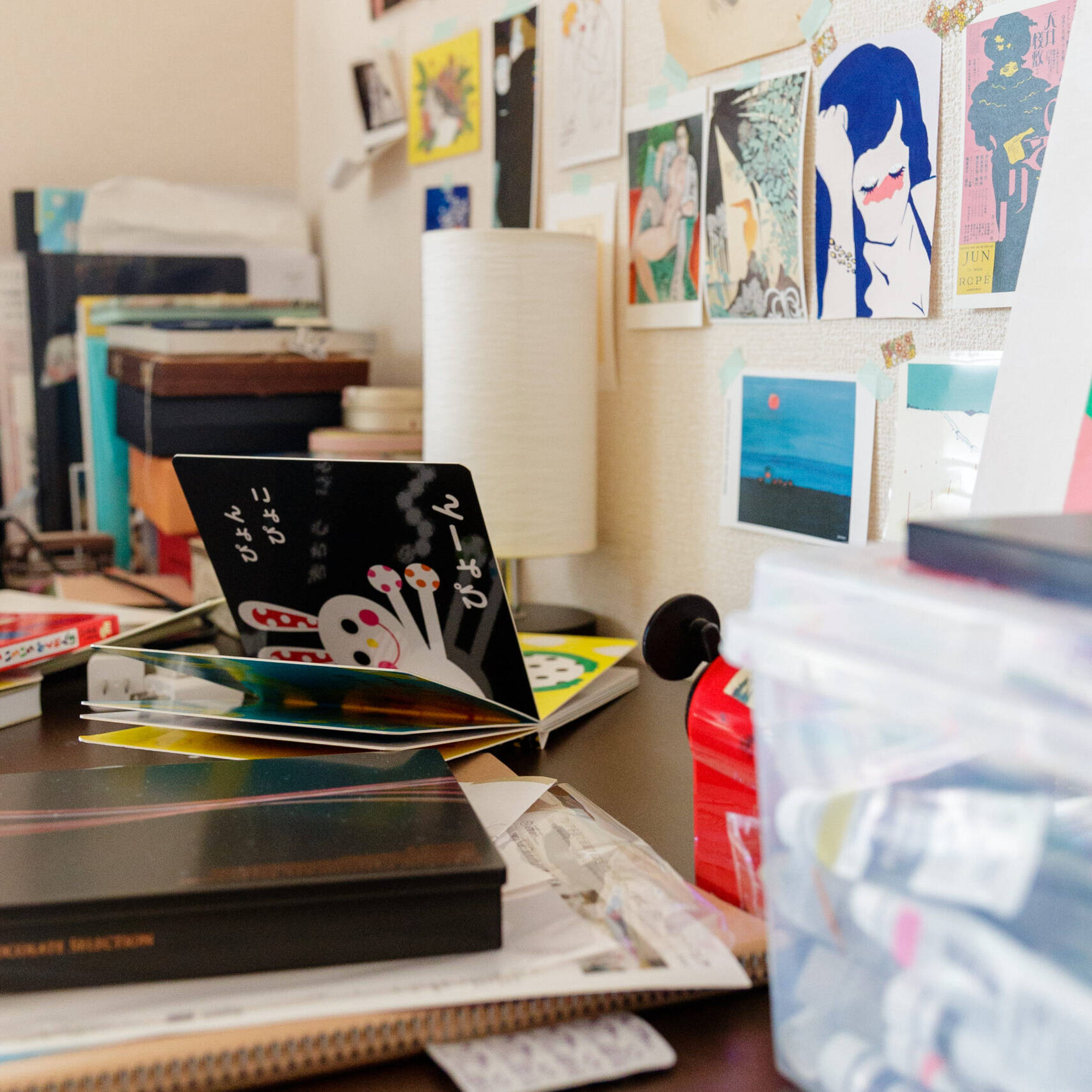Image of creative workspace with cluttered desk featuring art supplies, books, and colorful visuals. art prints and sketches decorate the wall, enhancing the artistic atmosphere. ideal for artists seeking inspiration and creative ideas in a home office or studio environment.