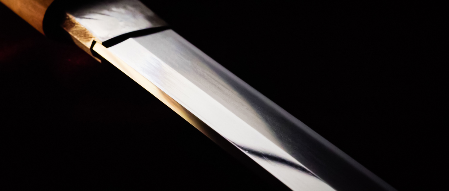 Image of close-up of a traditional japanese katana blade, showcasing its sharp, polished edge against a dark background. the high-quality craftsmanship of the sword is evident in its sleek, reflective surface, highlighting its cultural significance in martial arts and japanese history.