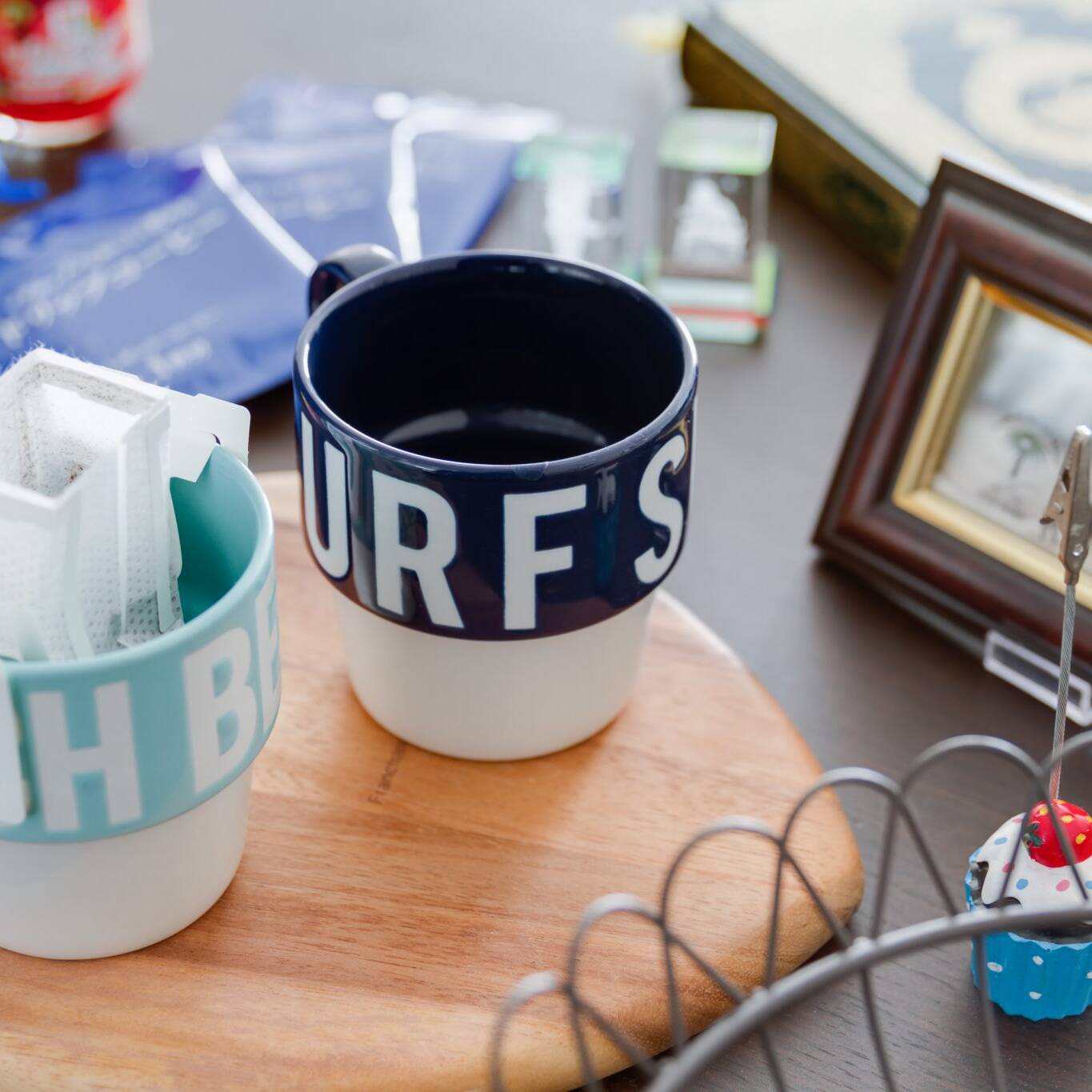 Image of the image showcases a cozy coffee setup featuring two personalized mugs on a wooden tray, perfect for a home cafe ambiance. one mug holds a pour-over coffee filter, adding to the artisanal coffee experience. nearby, a decorative mini cupcake and a framed photo