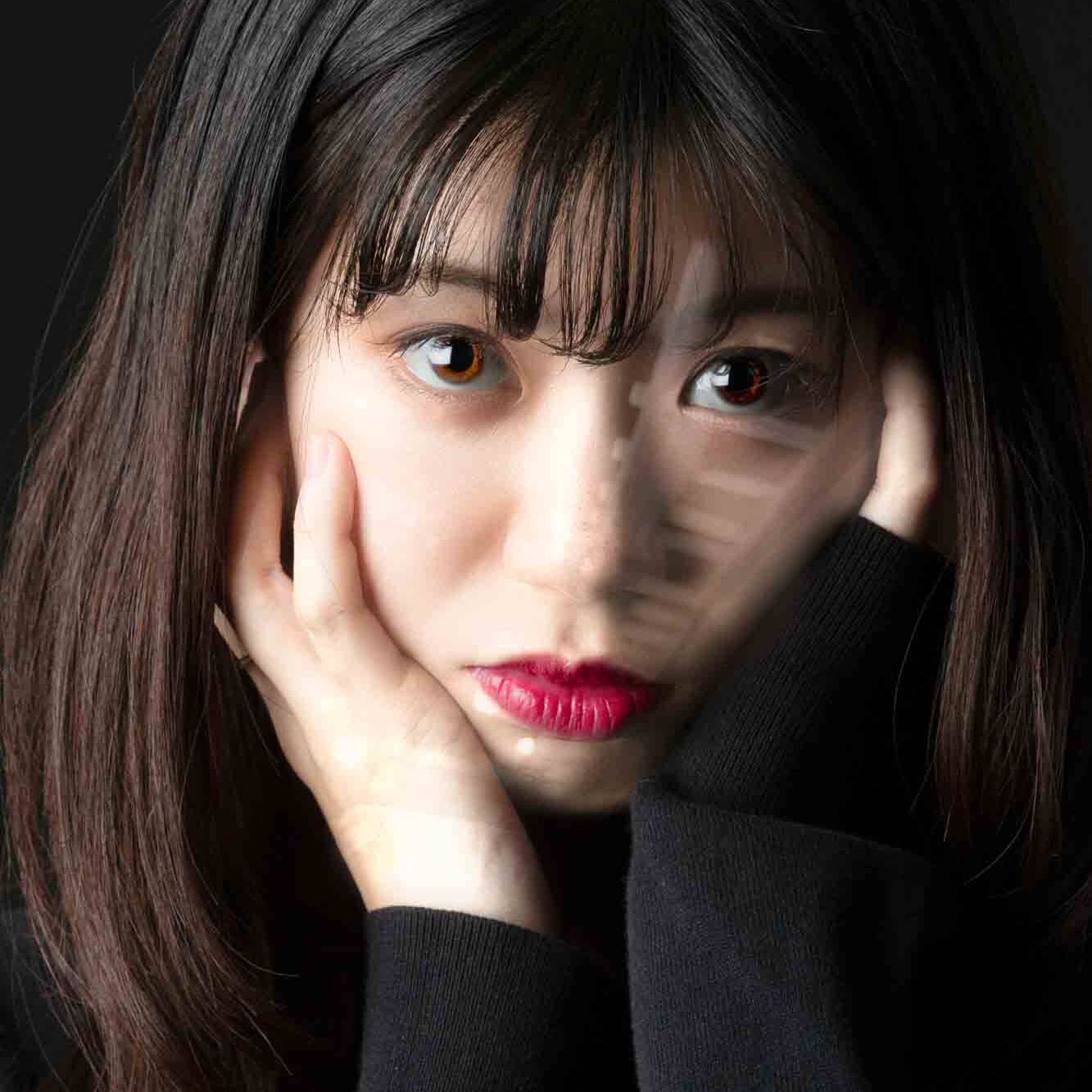 Image of portrait of a thoughtful young woman with long dark hair and bangs, resting her face in her hands. her expressive eyes and vibrant red lips contrast against a black background, creating a dramatic and intimate atmosphere. perfect for themes related to contemplation, emotion, and