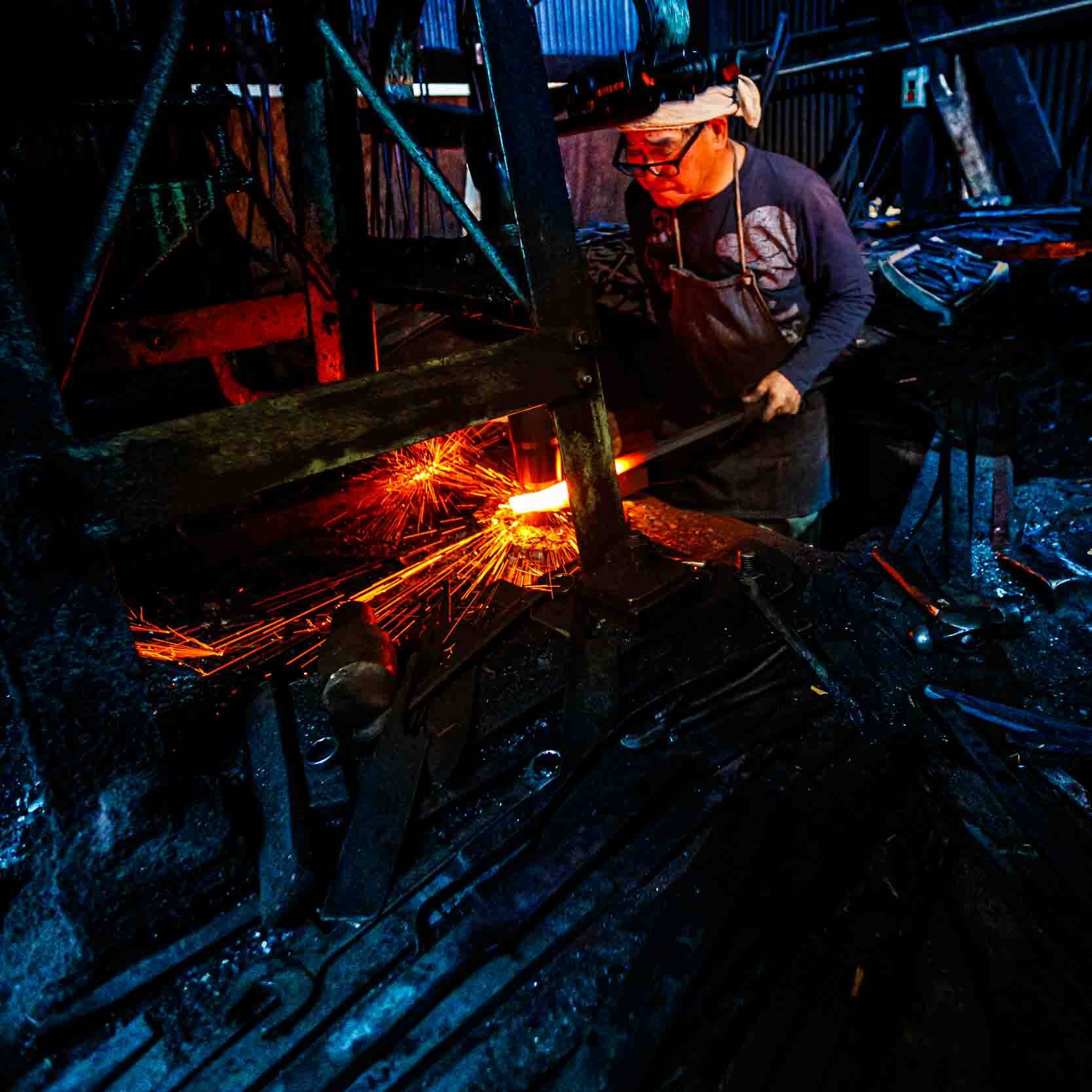 Image of a blacksmith working in a dimly lit forge, surrounded by sparks flying from heated metal. this industrial setting showcases traditional craftsmanship, with the artisan intensely focused on shaping the glowing iron. a perfect representation of skilled metalwork, the scene highlights the dramatic