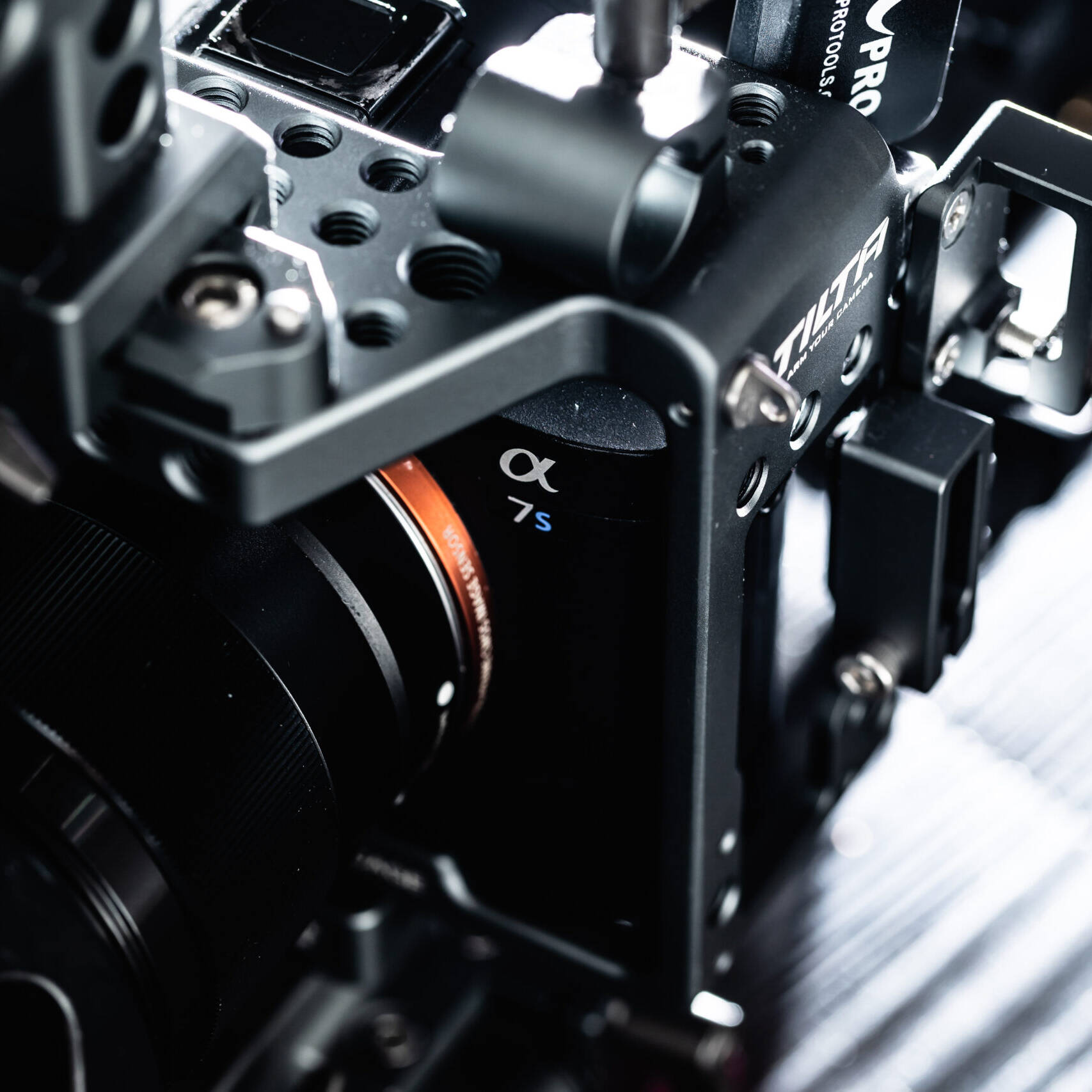 Image of this image showcases a close-up of a professional sony alpha 7s camera encased in a robust tilta camera cage. the setup features intricate mounting options, ideal for filmmakers and videographers seeking high-quality video production. the precision engineering of the metal