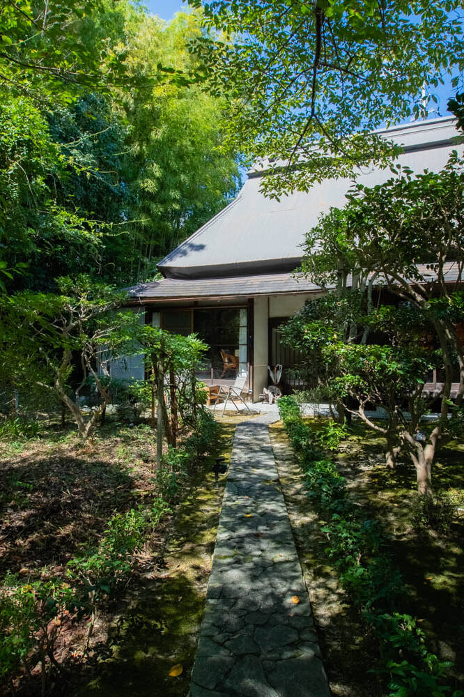 Image of serene japanese garden with lush greenery and a traditional house, showcasing a stone path leading through a tranquil yard. this idyllic scene is perfect for those seeking peace and nature-inspired architecture.