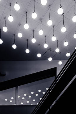 Image of this image showcases a modern interior with a ceiling adorned by a grid of glowing round pendant lights, creating a minimalist and elegant ambiance. the lights are reflected in a sleek glass partition, adding depth to the composition. the contemporary design and strategic lighting highlight architecture