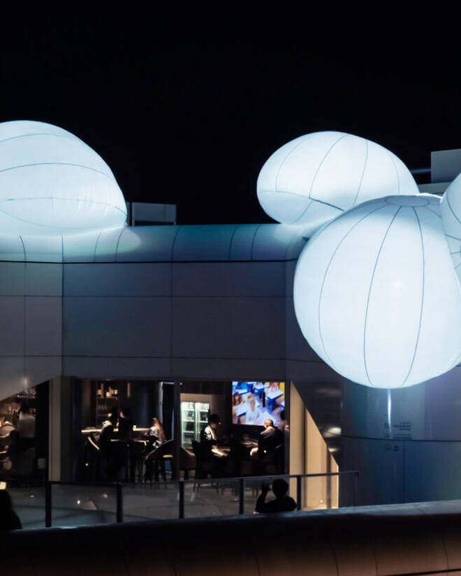 Image of illuminated rooftop structure at night featuring large, glowing balloon-like installations on a modern building. the unique architecture and ambient lighting create an eye-catching visual, perfect for showcasing innovative design and nightlife atmosphere. ideal for topics related to contemporary architecture, urban art