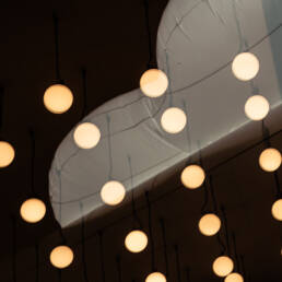 Image of modern indoor ceiling view showcasing abstract hanging globe lights against a dark background. the spherical lights, evenly spaced, provide a warm, ambient glow, creating a contemporary and artistic interior design aesthetic. ideal for keywords: modern ceiling design, abstract lighting, indoor decor