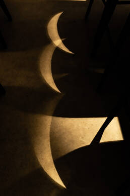 Image of abstract image of crescent shadows cast on a surface during an eclipse. the play of light and shadows creates a striking pattern, highlighting the celestial event's unique visual effects. perfect for keywords like eclipse shadows, crescent patterns, and solar phenomena.