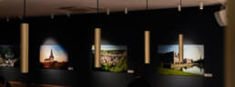 Image of exhibition room with modern pendant lighting, featuring blurred photography on a dark wall backdrop. the art gallery setting showcases landscape images, creating a serene and contemplative atmosphere. ideal for art enthusiasts interested in photography displays and contemporary gallery design.