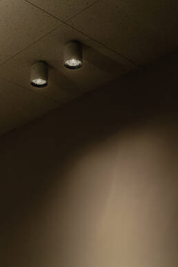 Image of this image showcases a pair of ceiling spotlights casting focused illumination on a smooth wall surface. the ambient lighting creates a warm, minimalist atmosphere, ideal for modern interior design settings. keywords: ceiling spotlights, ambient lighting, interior design, modern minimalist decor