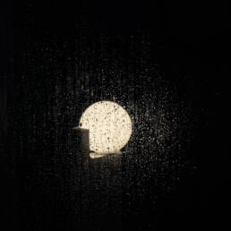 Image of a glowing light is visible behind a rain-covered window, creating a moody and atmospheric scene. the droplets on the glass enhance the nighttime ambiance, highlighting the contrast between the light and darkness. ideal for themes related to weather, rain, and nighttime photography