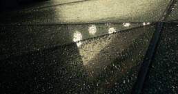 Image of rain-covered glass roof with a geometric design reflecting ambient lights, creating a moody and atmospheric urban scene. perfect for themes related to architecture, weather, and urban photography.