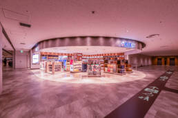 Image of this image showcases a modern duty-free shop at kansai international airport (kix) in japan. the store features a wide selection of travel retail products prominently displayed under bright lighting. the polished flooring and spacious layout enhance the shopping experience for travelers. ideal