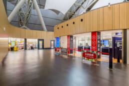 Image of this image depicts a modern airport terminal featuring a currency exchange booth and a duty-free shop. the area is spacious and well-lit, with a sleek design emphasizing convenience for travelers. keywords: airport terminal, currency exchange, duty-free shop, travel services,