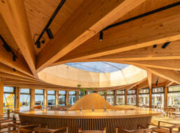 Image of modern wooden interior of a dome-shaped café, featuring sleek architectural design and natural light. the space includes wooden beams, a central bar with taps, and large windows creating an inviting atmosphere. perfect for keywords like 