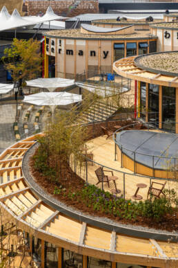 Image of this image showcases the distinctive architecture of the germany pavilion at expo 2025 in osaka, japan. the circular wooden structures feature green roofs, sustainable design elements, and outdoor seating areas surrounded by plants. the pavilion highlights germany's commitment to eco-friendly building