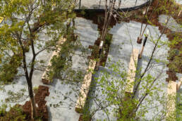 Image of aerial view of a serene urban park showcasing neatly arranged stone pathways, wooden benches, and lush green trees. this tranquil outdoor space highlights modern landscape architecture and offers a peaceful setting for relaxation and leisure in a bustling city environment. perfect for urban green space